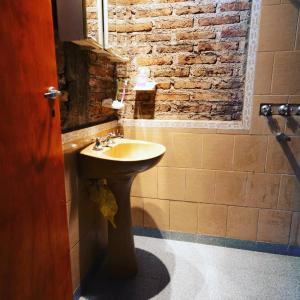 a bathroom with a sink and a brick wall at Chalet y Cabaña de montaña Esmeralda in Villa del Dique
