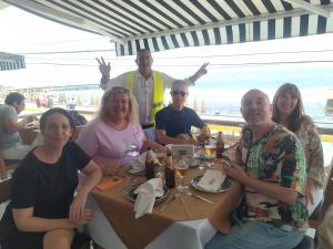 um grupo de pessoas sentadas à volta de uma mesa na praia em Ambigua Hospedaje em Trujillo