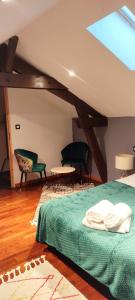 ein Schlafzimmer mit einem Bett und Stühlen im Dachgeschoss in der Unterkunft Maison de vacances in Bias