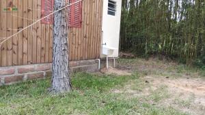 une maison avec un arbre à côté d'une clôture dans l'établissement H Office x WiFi x Churrasqueira x 6km Estr do Mar x 7km Pq de Rodeio x 12km Morro Borrusia, à Osório