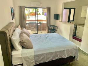 a bedroom with a bed with pillows and a kitchen at RAVENA 11 in Ribeirão Preto