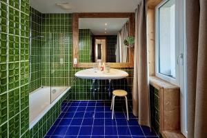 Baño de azulejos verdes con lavabo y bañera en Sporthotel Kogler, en Mittersill