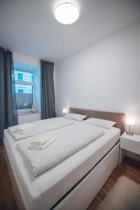 uma grande cama branca num quarto com uma janela em Apartment nähe Stadthalle em Viena