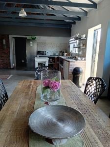 a wooden table with a vase with pink flowers on it at Spindrift Seaside Accommodation in Wilderness