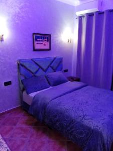 ein violettes Schlafzimmer mit einem Bett mit violetter Bettwäsche in der Unterkunft Miradore golfe in Martil