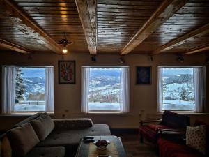 a living room with a couch and three windows at Cabana Dor de Apuseni in Cîmpeni