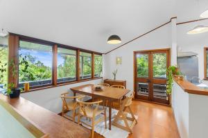 cocina y comedor con mesa y sillas en Treetop Sanctuary - Titirangi Holiday Home en Auckland