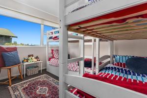 a bedroom with two bunk beds and a balcony at The Bachela - Ohope Beach Holiday Home in Ohope Beach