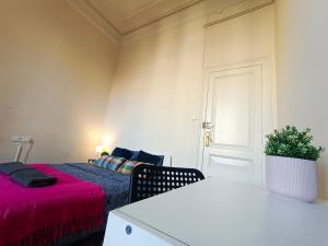 By Urquinaona Rooms في برشلونة: غرفة نوم بسرير وطاولة مع نبات
