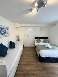 ロンドンにあるThe Chapter- Knightsbridge Suitesの白い壁の客室で、ベッド2台、青い枕が備わります。