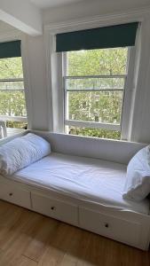 a bed sitting in a room with two windows at The Chapter- Knightsbridge Suites in London