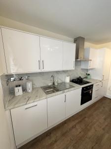 a kitchen with white cabinets and a sink at The Chapter- Knightsbridge Suites in London
