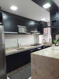 a kitchen with black cabinets and a counter top at Apto Brilho do Sol - Barra Velha - SC in Barra Velha