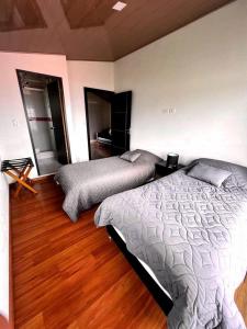 um quarto com 2 camas e piso em madeira em Cabañas Big Day Lago de Tota em Aquitânia