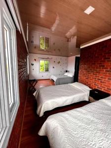 1 dormitorio con 3 camas y pared de ladrillo en Cabañas Big Day Lago de Tota en Aquitania