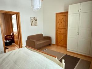 een slaapkamer met een bed, een bank en een stoel bij Liepeen pappila in Pudasjärvi