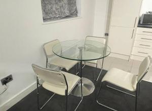 a glass table and four chairs in a kitchen at Modern 2-bed flat in Salford in Manchester