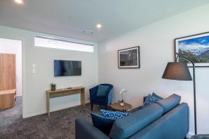 a living room with a blue couch and a table at Quest on Cambridge in Christchurch