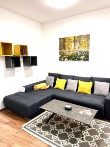 a living room with a black couch with yellow pillows at The Barts Apartments - Self Check-in in Vienna