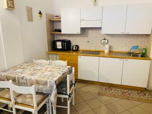a kitchen with white cabinets and a table with chairs at Bilocale Cristina Mazzin in Campestrin