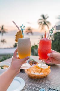 two people holding up two drinks on a table at Nest Sense Resort in Ko Chang