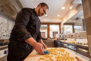 a man in a kitchen preparing food on a cutting board at LOCANDA LA SALITA in Monforte dʼAlba +3 photos