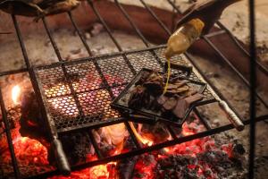 a person is cooking food on a grill at Fazenda Poço das Pedras in São João do Cariri