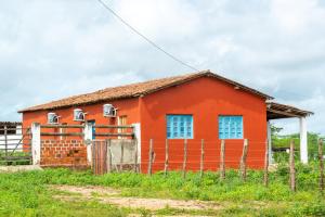 a red house with a fence in front of it at Fazenda Poço das Pedras in São João do Cariri