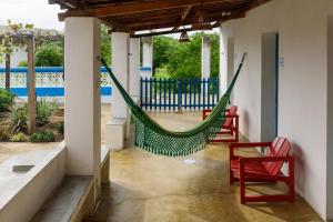 a hammock in a porch with two red chairs at Fazenda Poço das Pedras in São João do Cariri
