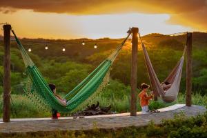 two children playing in hammocks with the sunset in the background at Fazenda Poço das Pedras in São João do Cariri