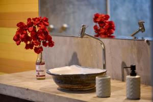 a bathroom counter with a sink with a bowl and red flowers at Fazenda Poço das Pedras in São João do Cariri