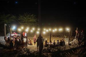 un grupo de personas sentadas alrededor de un escenario por la noche en Fazenda Poço das Pedras en São João do Cariri