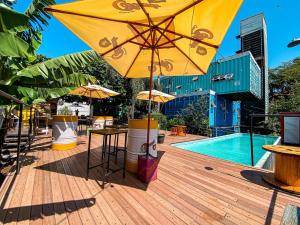 a yellow umbrella sitting on a deck next to a pool at Tetris Container Hostel in Foz do Iguaçu