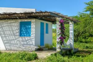 a small house with a blue door and flowers at Fazenda Poço das Pedras in São João do Cariri