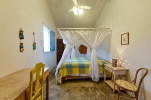 a bedroom with a bed with a canopy and a table at Fazenda Poço das Pedras in São João do Cariri