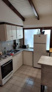 uma cozinha com armários brancos, um fogão e um frigorífico em CABAÑA CASA DE PIEDRA em San Carlos de Bariloche