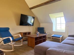 a living room with a couch and a tv on the wall at La demoiselle ô bois - Gite rural Chimay in Seloignes
