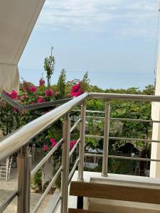 un balcón con flores rosas y el océano en ELÉA Guesthouse himare, en Himare