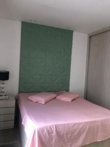 um quarto com uma cama rosa e uma parede verde em Próximo ao centro, perto de tudo! em Belo Horizonte