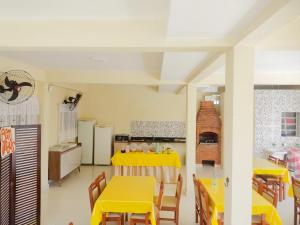 a dining room with yellow tables and chairs and a kitchen at Recanto Solarium in Itanhaém