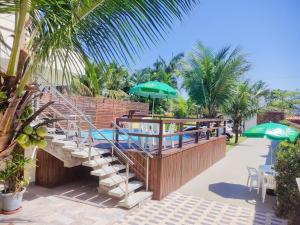 a patio with a pool and a deck with umbrellas at Pousada Recanto Solarium in Itanhaém