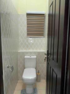 a bathroom with a white toilet and a window at Cozy Luxe Apartment w/ WiFi & AC in Tema