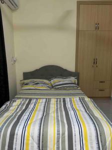a bed with a striped comforter in a bedroom at Cozy Luxe Apartment w/ WiFi & AC in Tema