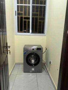 a washing machine in a room with a window at Cozy Luxe Apartment w/ WiFi & AC in Tema