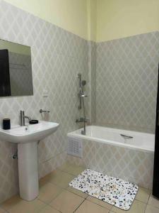 a bathroom with a sink and a bath tub at Cozy Luxe Apartment w/ WiFi & AC in Tema