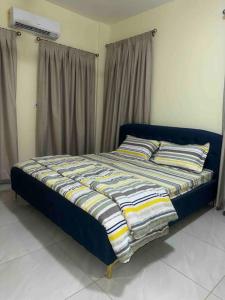 a bed sitting in a room with curtains at Cozy Luxe Apartment w/ WiFi & AC in Tema