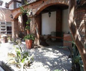 um pátio exterior com um banco e uma parede de tijolos em Casa Amadis em Querétaro