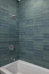 Kimpton Hotel Monaco Salt Lake City, an IHG Hotel في مدينة سولت ليك: حمام به جدران من البلاط الأخضر وحوض استحمام