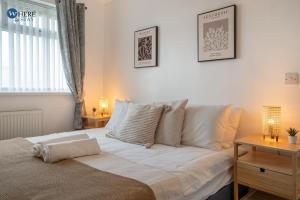 a bedroom with a bed with white sheets and a window at Gorgeous 2 bed apartment Durham 