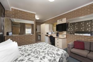 a bedroom with a bed and a desk and a kitchen at Grand Manor Motor Inn in Queanbeyan